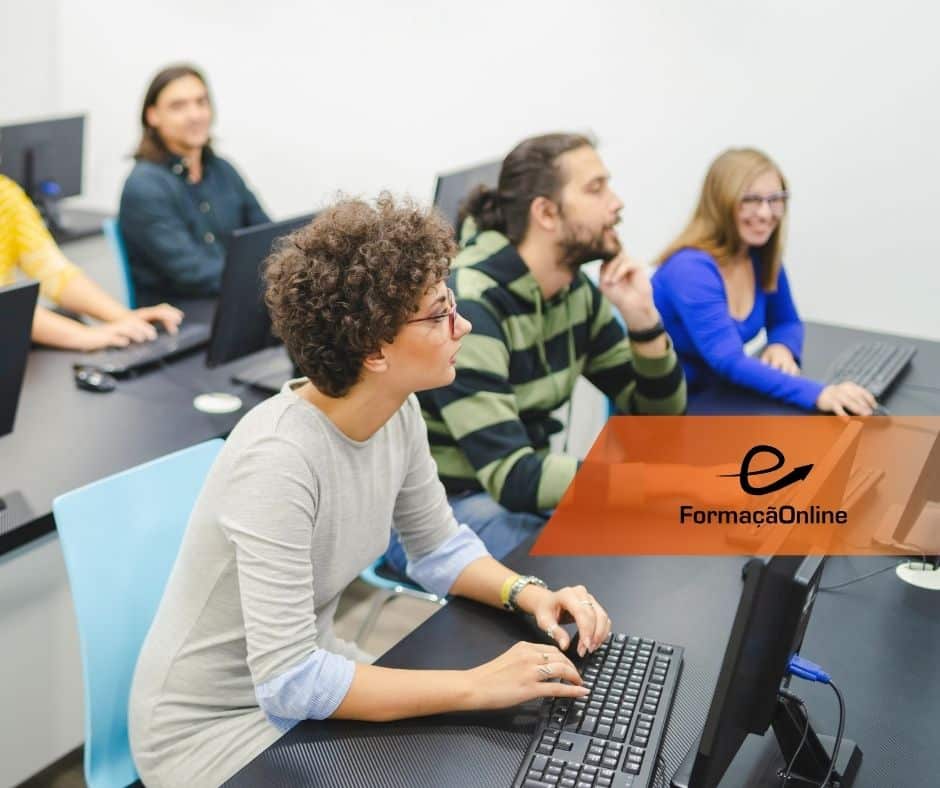 Group of students at computer desks in a classroom; orange translucent banner with 'FormaçãoOnline' overlays the scene.