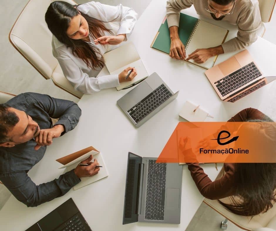 Overhead view of four people around a white table with laptops and notebooks; an orange 'e FormaçaoOnline' banner sits on the right.